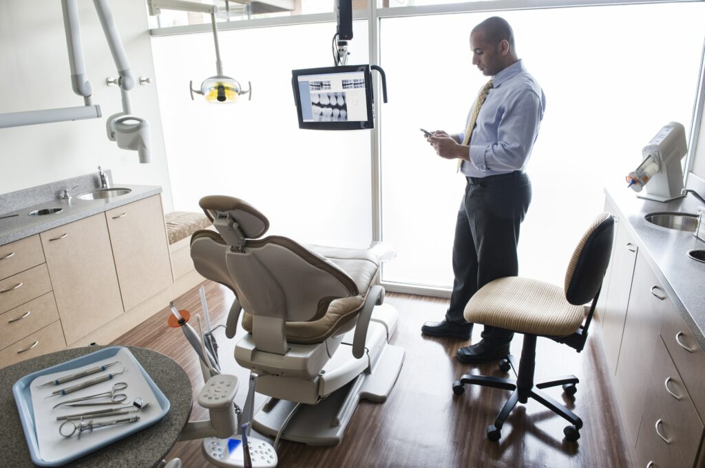 A Middle Eastern male dentist checking his cell phone in a dental examination room